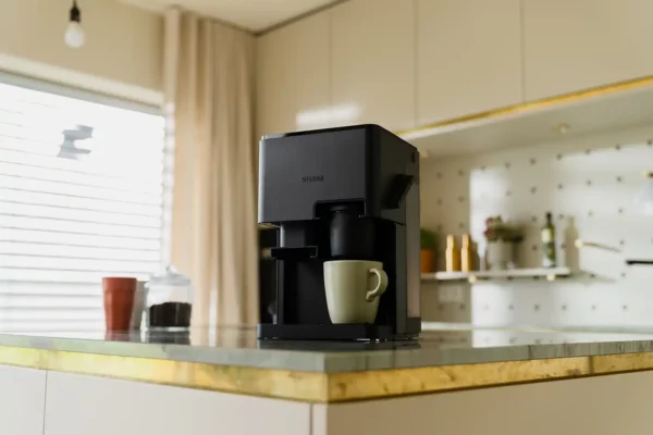 Stilvoller NIVONA CUBE 4106 Kaffeeautomat auf einer Küchenarbeitsplatte, hervorgehoben durch modernes Küchendesign mit einer Tasse darunter, bereit, frischen Kaffee zu servieren.
