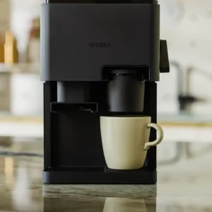 Eleganter NIVONA CUBE 4106 Kaffeeautomat in voller Pracht auf einer Marmorarbeitsplatte, bereit, mit einem cremefarbenen Becher darunter, ein Synonym für moderne Kaffeekunst in jedem Zuhause.